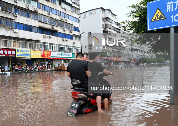 Citizens are traveling on a flooded road in Neijiang, Sichuan province, China, on July 13, 2024. 