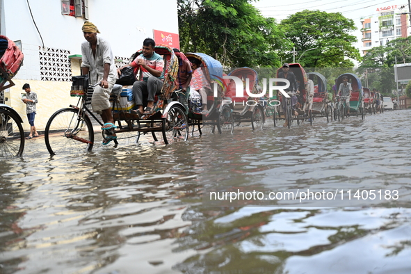 People and vehicles are trying to move through the waterlogged street in Dhaka, Bangladesh, on July 26, 2024 