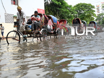 People and vehicles are trying to move through the waterlogged street in Dhaka, Bangladesh, on July 26, 2024 (