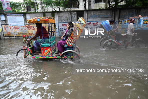 People and vehicles are trying to move through the waterlogged street in Dhaka, Bangladesh, on July 26, 2024 