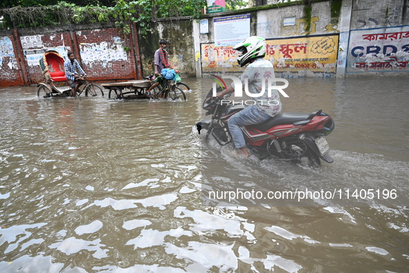 People and vehicles are trying to move through the waterlogged street in Dhaka, Bangladesh, on July 26, 2024 