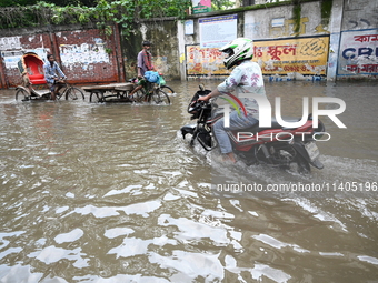 People and vehicles are trying to move through the waterlogged street in Dhaka, Bangladesh, on July 26, 2024 (