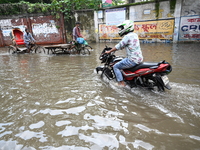 People and vehicles are trying to move through the waterlogged street in Dhaka, Bangladesh, on July 26, 2024 (