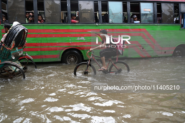 People and vehicles are trying to move through the waterlogged street in Dhaka, Bangladesh, on July 26, 2024 