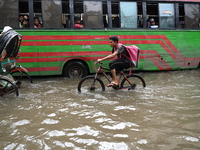 People and vehicles are trying to move through the waterlogged street in Dhaka, Bangladesh, on July 26, 2024 (