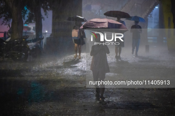 Citizens are walking through the rainstorm in central Chongqing, China, on July 13, 2024. 