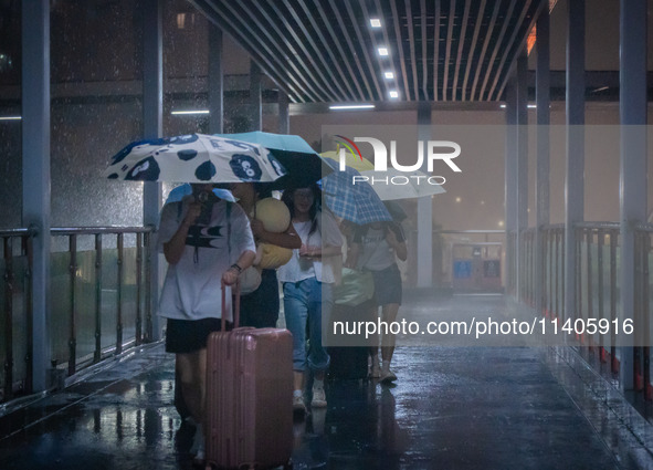 Citizens are walking through the rainstorm in central Chongqing, China, on July 13, 2024. 