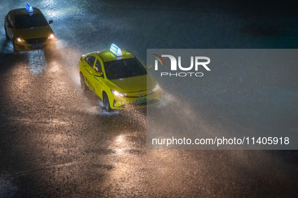 Vehicles are driving in the rainstorm in central Chongqing, China, on July 13, 2024. 