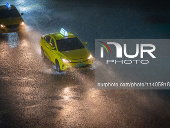 Vehicles are driving in the rainstorm in central Chongqing, China, on July 13, 2024. (