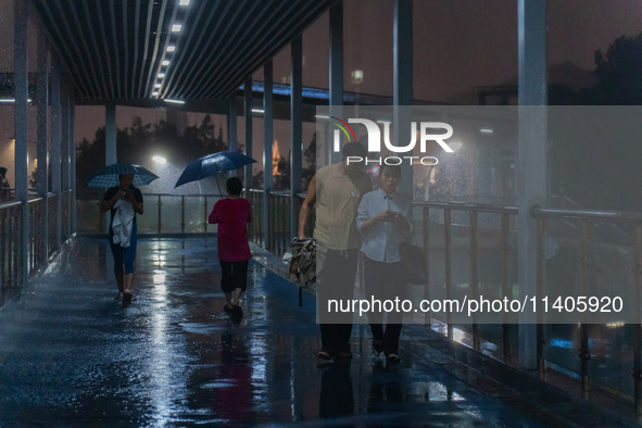 Citizens are walking through the rainstorm in central Chongqing, China, on July 13, 2024. 