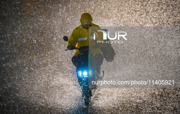 A courier is riding in the rainstorm in central Chongqing, China, on July 13, 2024. 