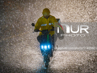 A courier is riding in the rainstorm in central Chongqing, China, on July 13, 2024. (