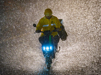 A courier is riding in the rainstorm in central Chongqing, China, on July 13, 2024. (