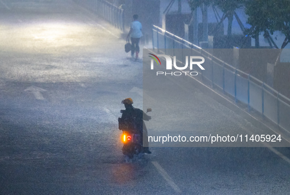 A courier is riding in the rain in central Chongqing, China, on July 13, 2024. 