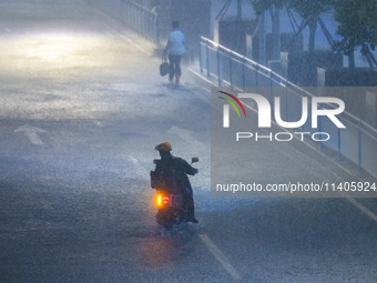 A courier is riding in the rain in central Chongqing, China, on July 13, 2024. (