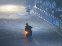 A courier is riding in the rain in central Chongqing, China, on July 13, 2024. (