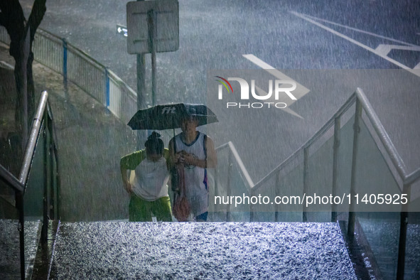 Citizens are walking through the rainstorm in central Chongqing, China, on July 13, 2024. 