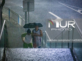 Citizens are walking through the rainstorm in central Chongqing, China, on July 13, 2024. (