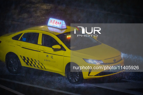 A taxi is driving in the rainstorm in central Chongqing, China, on July 13, 2024. 