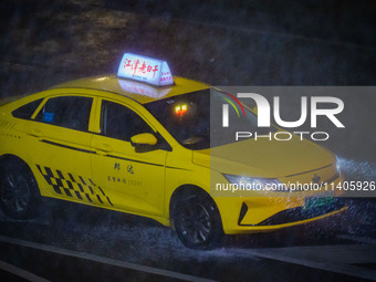 A taxi is driving in the rainstorm in central Chongqing, China, on July 13, 2024. (