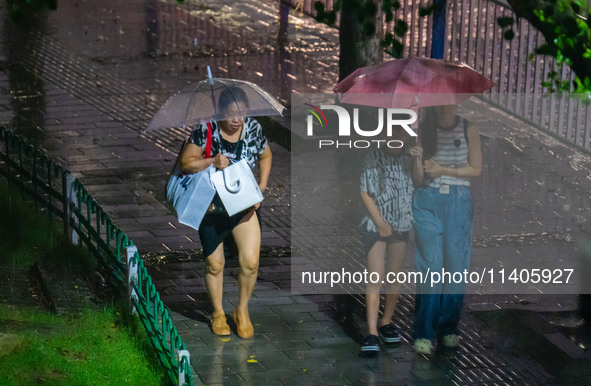 Citizens are walking through the rainstorm in central Chongqing, China, on July 13, 2024. 