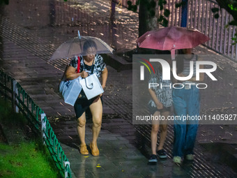 Citizens are walking through the rainstorm in central Chongqing, China, on July 13, 2024. (