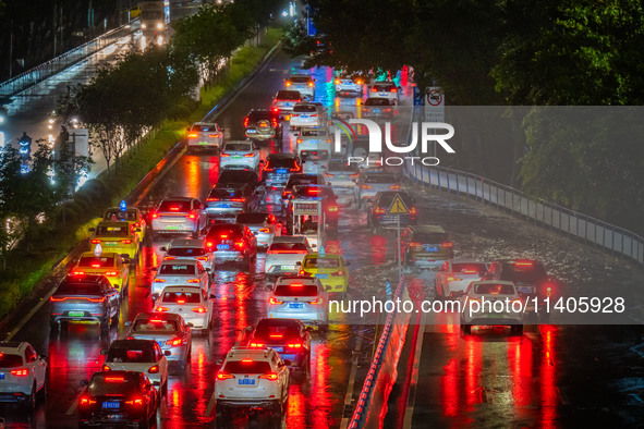 Vehicles are driving slowly in the rainstorm in central Chongqing, China, on July 13, 2024. 