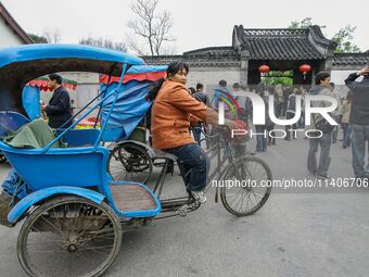 A cyclo driver is waiting for a guest near the national garden in Yangzhou, China. (