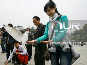 Visitors are feeding a white pigeon at the square of Lingshan Temple in Wuxi, China. (