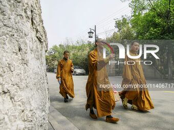 Monks are walking past the street near the North Temple Pagoda in Suzhou, China. (