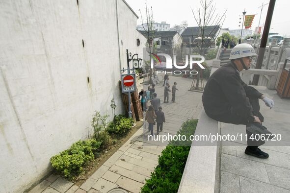 A public security officer is resting on a safety curve in Zhouzhuang town in Suzhou, China. 