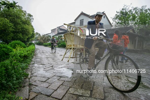 An elderly man is transporting a wooden chair in Zhouzhuang town in Suzhou, China. 