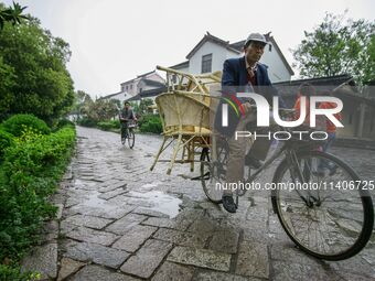 An elderly man is transporting a wooden chair in Zhouzhuang town in Suzhou, China. (