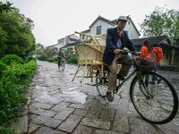 An elderly man is transporting a wooden chair in Zhouzhuang town in Suzhou, China. (