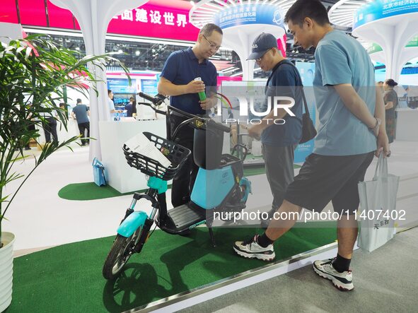 Visitors are visiting a ''hydrogen-powered moped'' at the 26th China Beijing International Science and Technology Industry Expo in Beijing,...