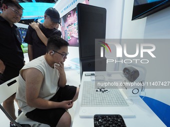 Visitors are playing with a Go robot at the 26th China Beijing International Science and Technology Industry Expo in Beijing, China, on July...