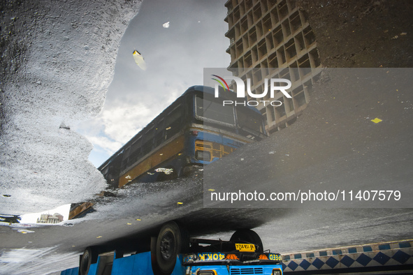 A bus is being reflected in a puddle of rainwater during the monsoon in Kolkata, India, on July 14, 2024. 