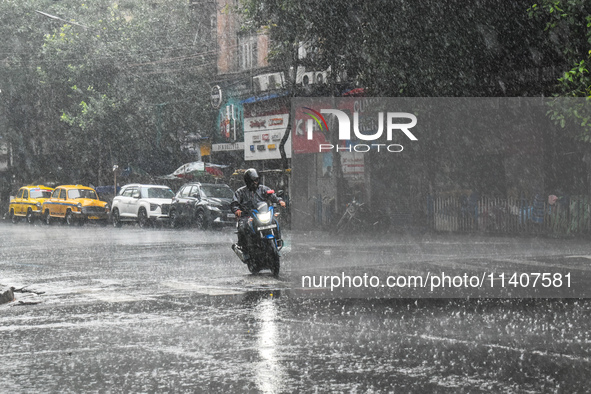 A person is riding a motorcycle during the heavy rain in Kolkata, India, on July 14, 2024. 