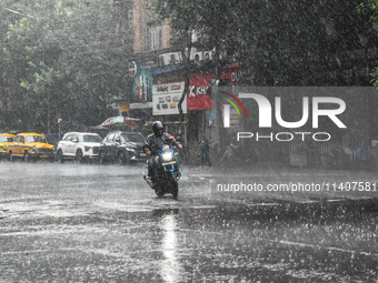 A person is riding a motorcycle during the heavy rain in Kolkata, India, on July 14, 2024. (