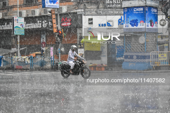 A person is riding a motorcycle during the heavy rain in Kolkata, India, on July 14, 2024. 