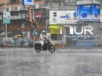 A person is riding a motorcycle during the heavy rain in Kolkata, India, on July 14, 2024. (