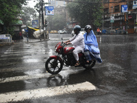 People are riding on a motorcycle during the heavy rain in Kolkata, India, on July 14, 2024. (