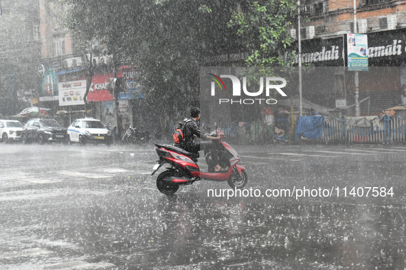 A person is riding an Escooter during the heavy rain in Kolkata, India, on July 14, 2024. 