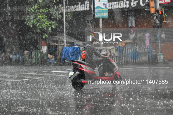 A person is riding an Escooter during the heavy rain in Kolkata, India, on July 14, 2024. 