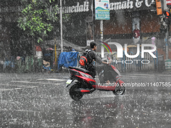 A person is riding an Escooter during the heavy rain in Kolkata, India, on July 14, 2024. (