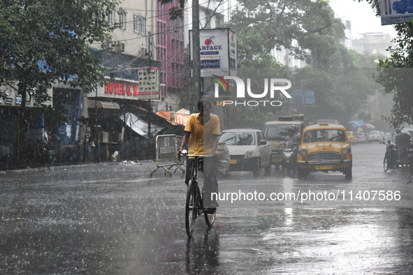 A person is riding his cycle during the heavy rain in Kolkata, India, on July 14, 2024. 