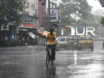 A person is riding his cycle during the heavy rain in Kolkata, India, on July 14, 2024. (