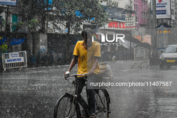 A person is riding his cycle during the heavy rain in Kolkata, India, on July 14, 2024. 