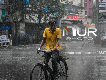 A person is riding his cycle during the heavy rain in Kolkata, India, on July 14, 2024. (