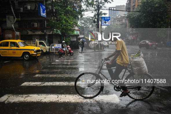 A person is riding his cycle during the heavy rain in Kolkata, India, on July 14, 2024. 